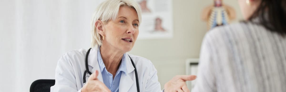 Heart Disease Symptoms You Need to Know (38) A doctor in a lab coat tells her patient about an epidural pain management plan