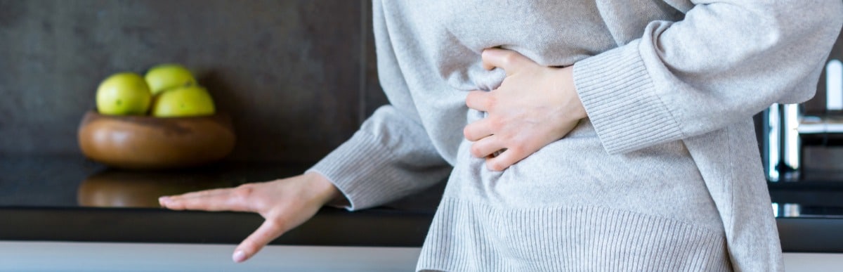 Heart Disease Symptoms You Need to Know-4 A woman holds her stomach from indigestion, which is one of the main heart disease symptoms