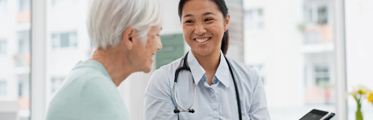 Heart Disease Symptoms You Need to Know (45) A doctor in a lab coat smiles and tells her patient about the early signs of autoimmune arthritis