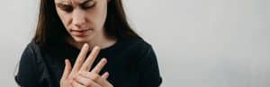 A woman holds her hand due to joint stiffness which is one of the early signs of autoimmune arthritis