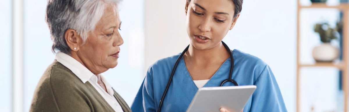 Heart Disease Symptoms You Need to Know (50) A doctor wearing scrubs and a stethoscope speaks with her patient about the early signs of autoimmune arthritis