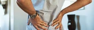 A man holds his lower back in pain as he considers spinal injections for pain