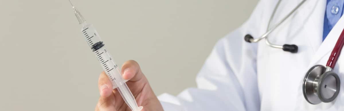 Heart Disease Symptoms You Need to Know (58) A doctor in a lab coat holds an injection needle used for spinal injections for pain