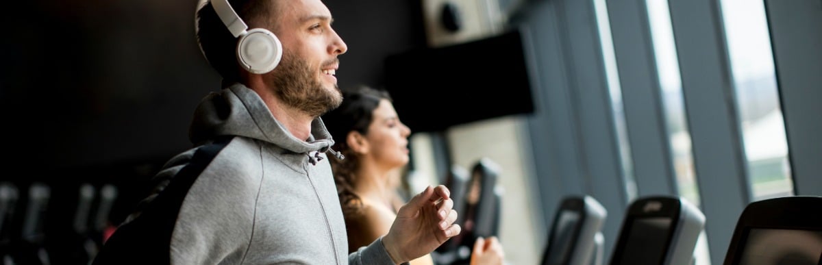 Heart Disease Symptoms You Need to Know (59) A man wearing headphones smiles as he jogs on a treadmill after spinal injections for pain