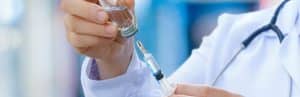 A doctor in a lab coat prepares an injection needle for an epidural steroid injection