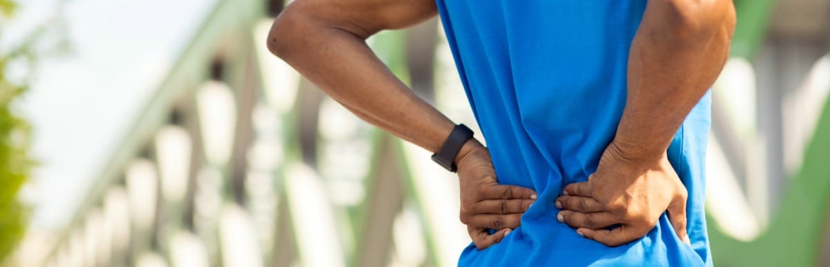 Heart Disease Symptoms You Need to Know (65) A runner holds his lower back in pain