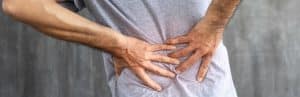 A person holds their back and searches for middle back pain relief treatment