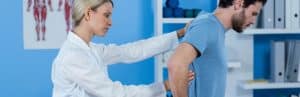A doctor examines a patient's back to determine the best vertebral compression fracture treatments