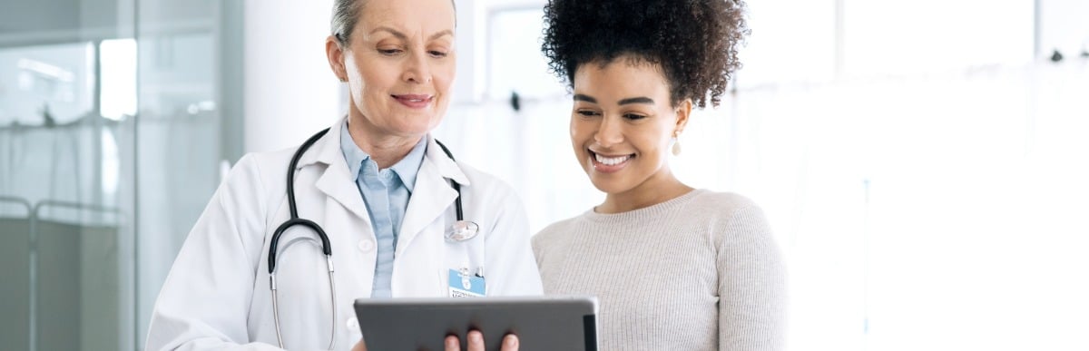 Heart Disease Symptoms You Need to Know (75) A doctor reviews vertebral compression fracture treatments on a tablet with a patient