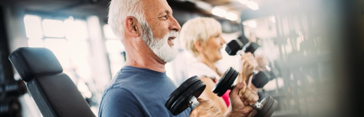 Heart Disease Symptoms You Need to Know (76) A man smiles as he lifts weights at the gym