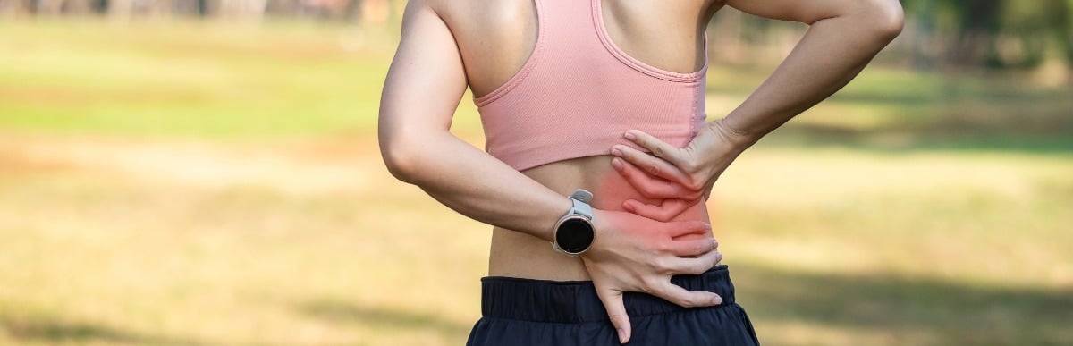 A runner in need of middle back pain relief holds her back during a jog 