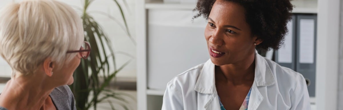 Heart Disease Symptoms You Need to Know (80) A doctor in a lab coat talks with an older patient about kyphoplasty recovery time