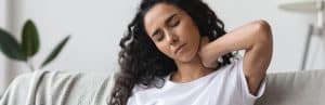A woman rubs her neck in pain due to myofascial pain syndrome