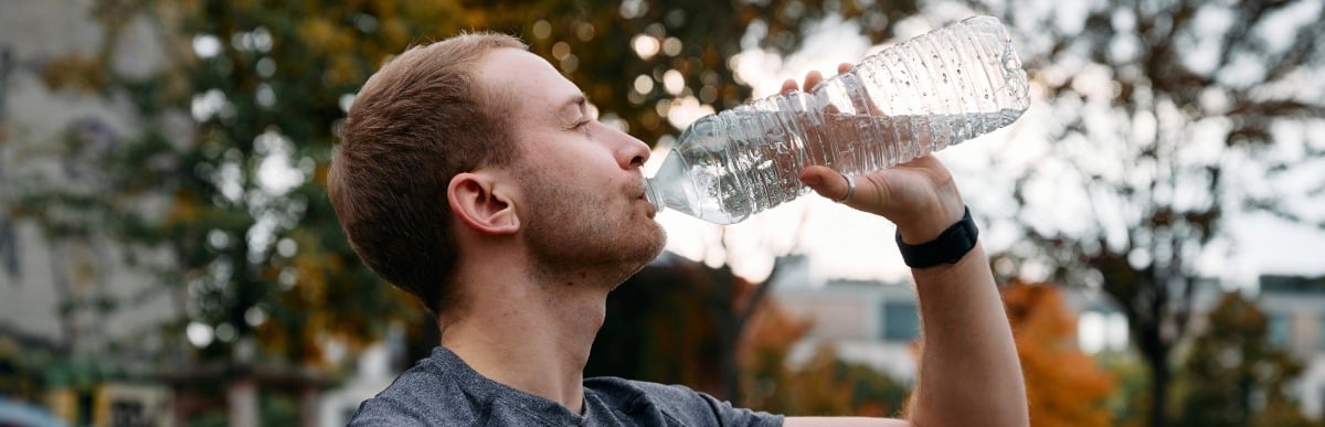 Heart Disease Symptoms You Need to Know (86) A man drinks water out of a large bottle to ease pain from myofascial pain syndrome