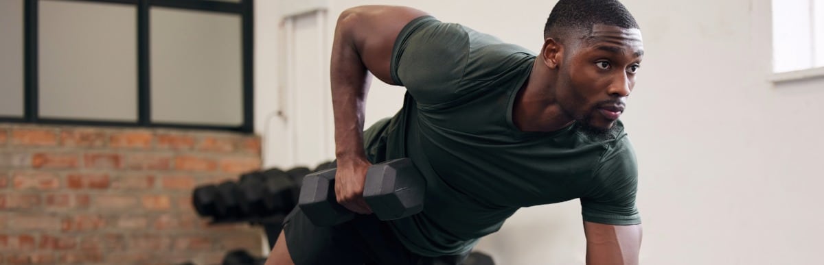 Heart Disease Symptoms You Need to Know (99) A man lifts a weight at the gym after peptide therapy for muscle recovery