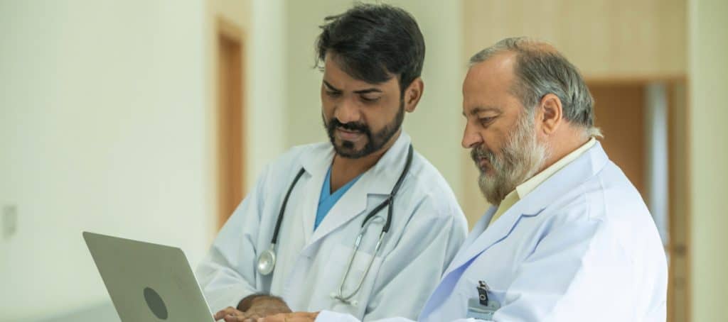Two doctors in lab coats with stethoscopes look at diagnostic tests for diabetic neuropathy