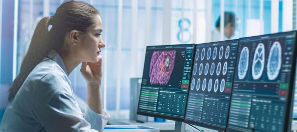 A doctor looks at monitors to examine brain scans for a diabetic neuropathy diagnosis