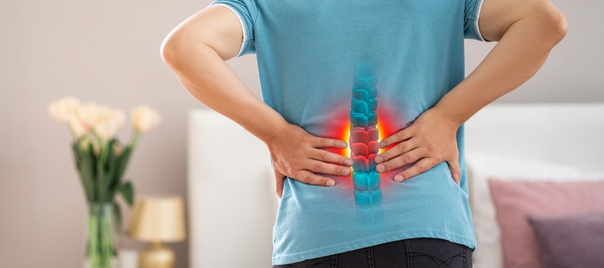 How Do You Treat Spinal Stenosis Without Surgery-3-Ouch A person holds their back in pain due to spinal stenosis