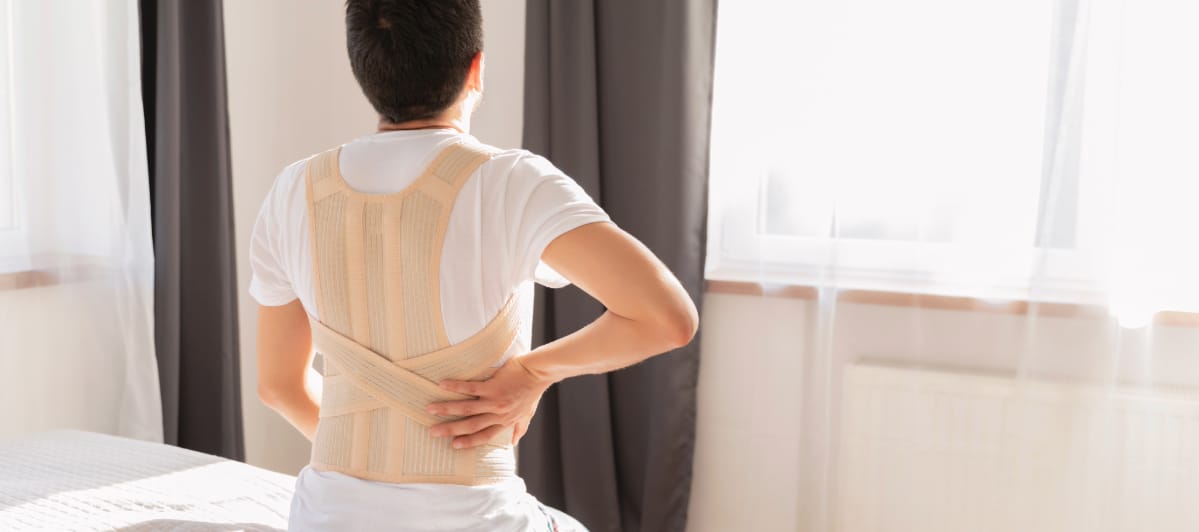 How Fast Does Degenerative Disc Disease Progress-6-Back brace A man grabs his back while sitting on bed and wearing a back brace