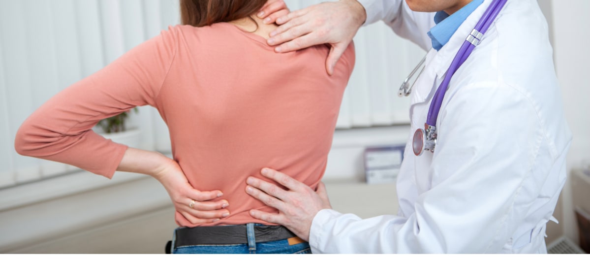 Ideal Candidates for Kyphoplasty-3-Ouch A woman holds her back in pain as a doctor examines her