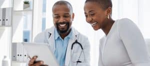 A doctor in a lab coat smiles as he talks to a patient about kyphoplasty treatment