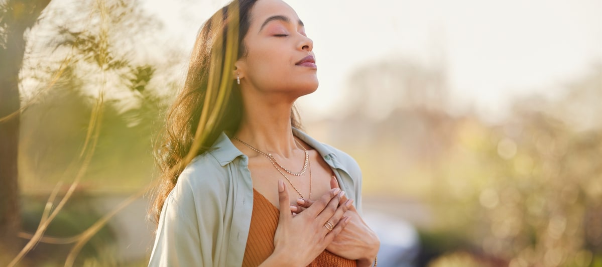 A woman closes her eyes and puts her hands to her chest as she enjoys life after hormone replacement therapy