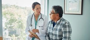 A doctor in a lab coat talks to her patient about hormone replacement therapy