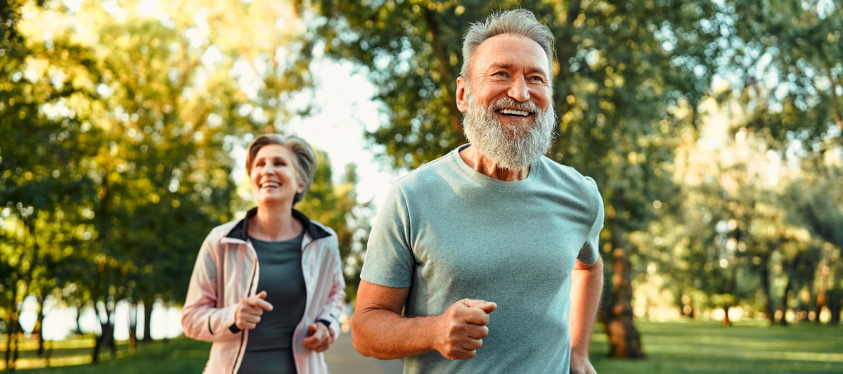 Is Hormone Replacement Therapy Right for Me-4-Joggers An older couple smile as they jog through the park after hormone replacement therapy