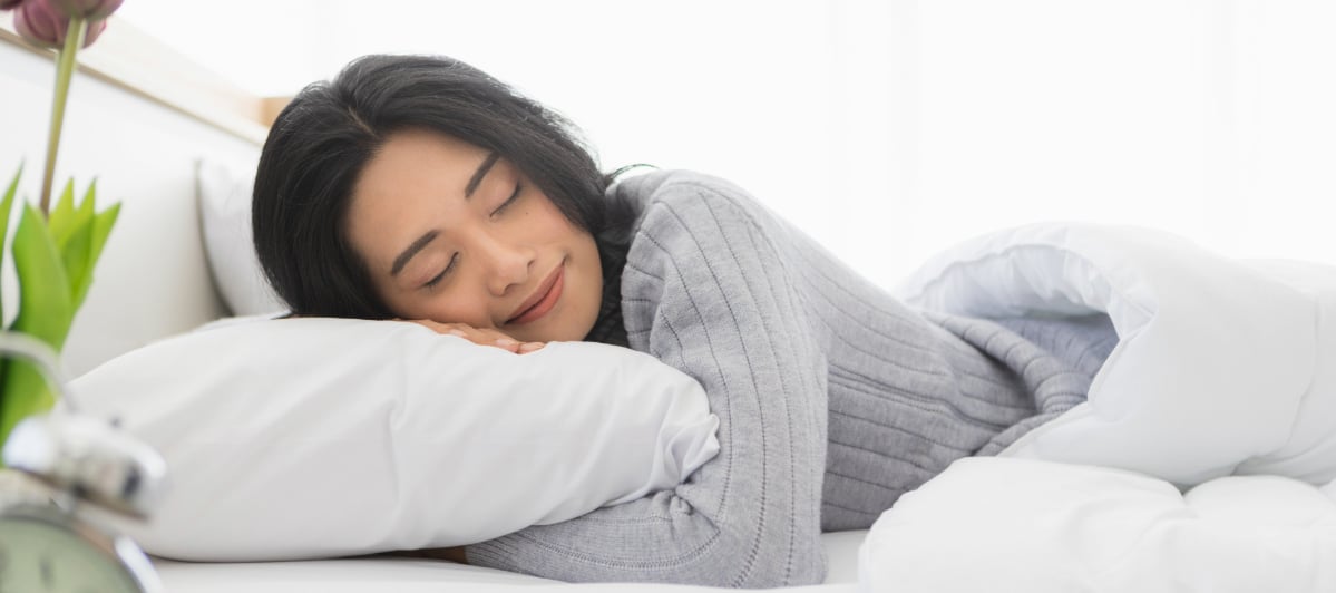 Is Hormone Replacement Therapy Right for Me-5-Sleep A woman laying in bed smiles after restful sleep due to hormone replacement therapy
