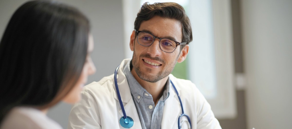 Is Hormone Replacement Therapy Right for Me-6-Doc A doctor in a lab coat smiles as he tells a patient about hormone replacement therapy