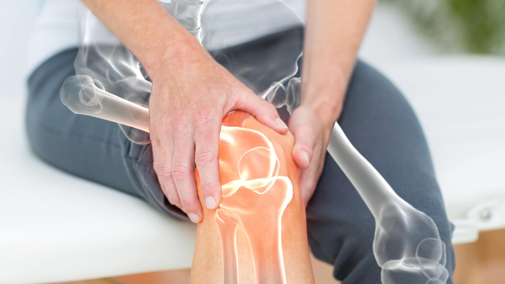 Knee-1 A man holding his knee with an overlay of the knee bones in orange highlights.