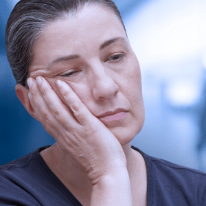 A woman suffering from fatigue with her hand on her face.