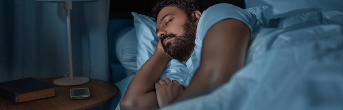 Making Sense of Glucose Management Indicators-3 A man sleeps peacefully in bed after checking his glucose management indicators