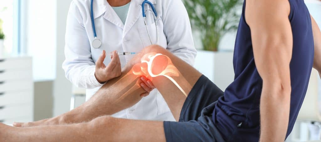 A pain management doctor administering a knee injection to a patient.