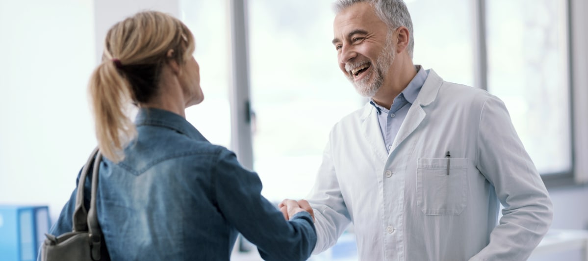 Personal-Injury-Doctors-6-Smiling-doctor A pain management doctor meeting with a female patient