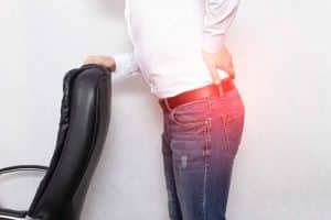 A suffering from back pain man holding his lower back