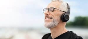 A man wearing glasses and headphones smiles due to treatment from a peripheral nerve stimulator for CRPS