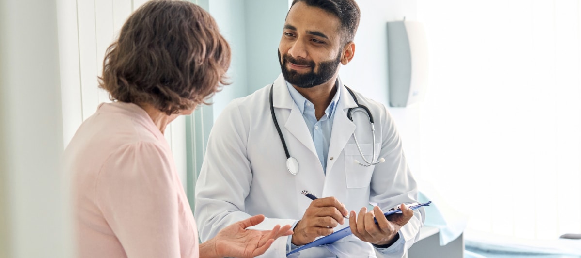Relieve Your Back Pain with Sacroiliac Joint Injections-5-Doctor A doctor in a lab coat smiles as he talks to a patient about sacroiliac joint injections