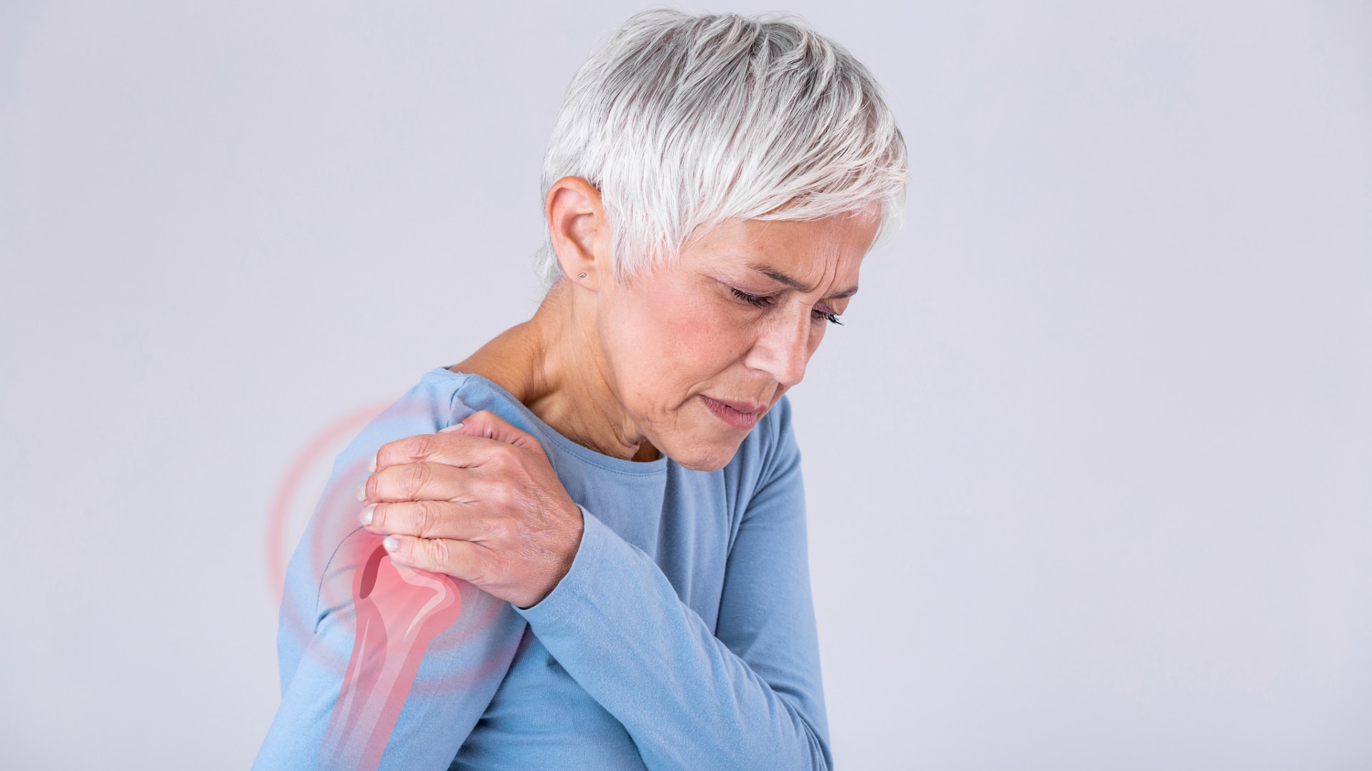 Shoulder-1 An elderly women in a blue shirt holding her shoulder while in pain.