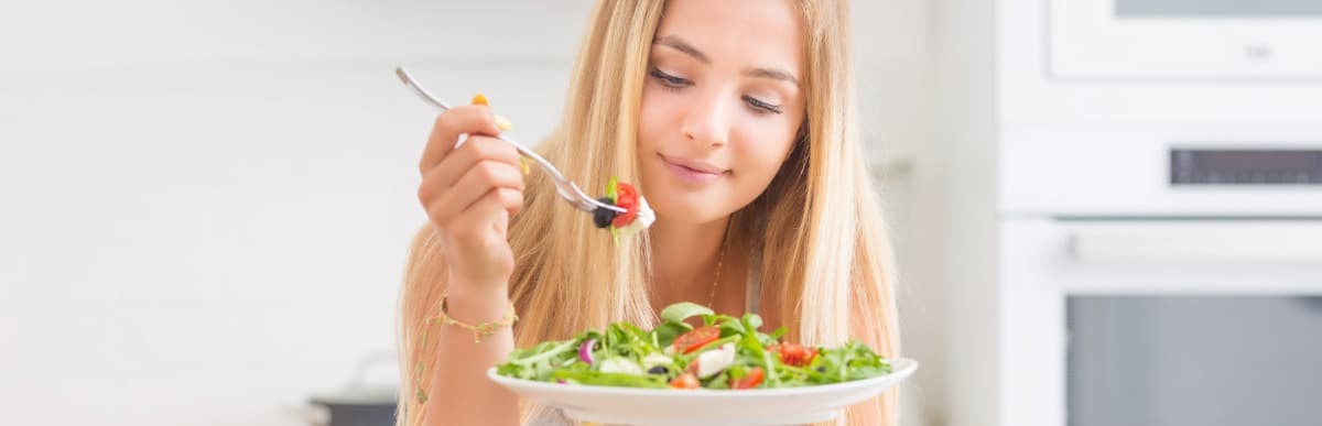 Stage 2 Hypertension When Blood Pressure Gets Serious-5 A woman takes a forkful of a salad which includes leafy greens to lower hypertension