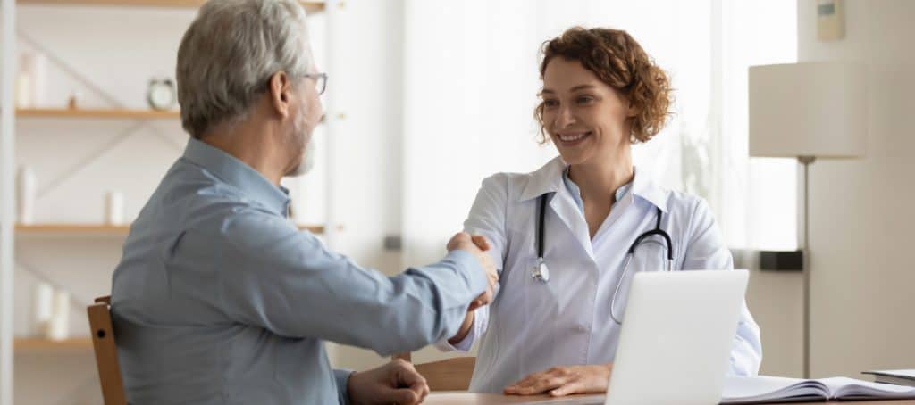 A doctor in a lab coat smiles as she shakes hands with her diabetic neuropathy patient