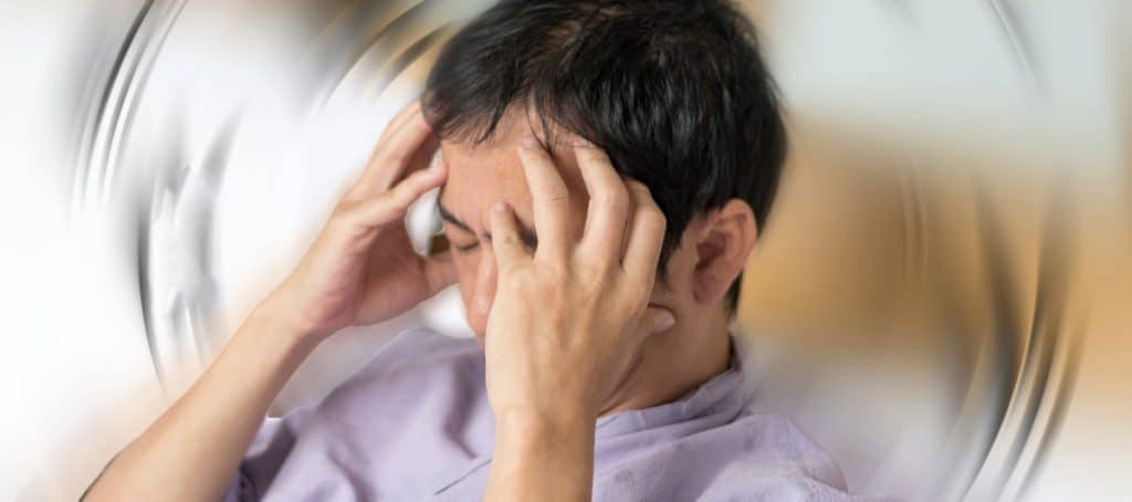 A man grabs his head in pain from vertigo due to diabetic neuropathy