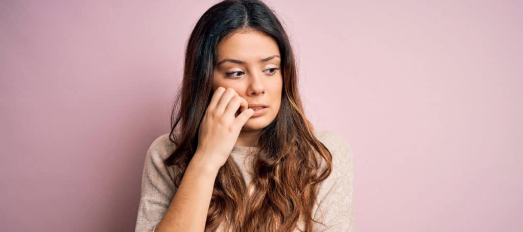 A woman bites her nails because she's worried about non-diabetic neuropathy symptoms such as loss of balance