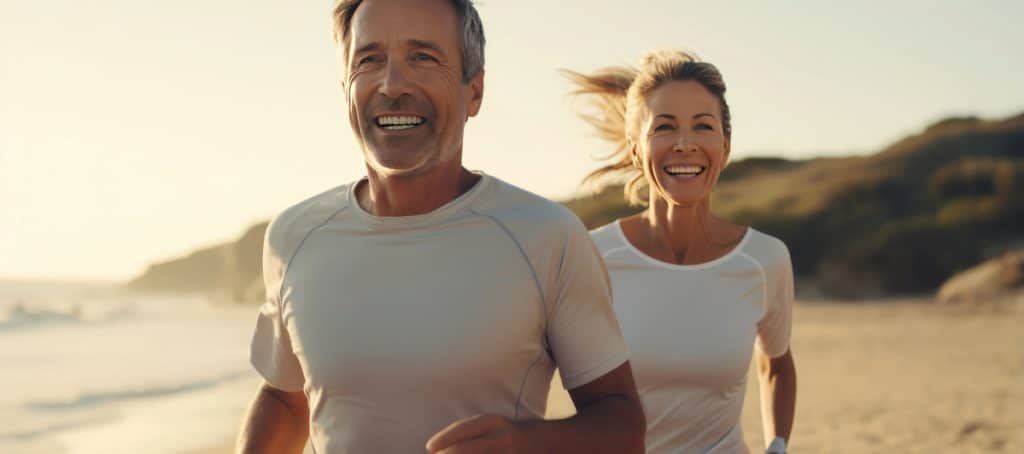 A middle age couple running on the beach during a sunrise