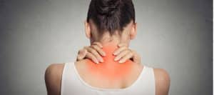 A woman grabs both sides of the back of her neck due to chronic pain