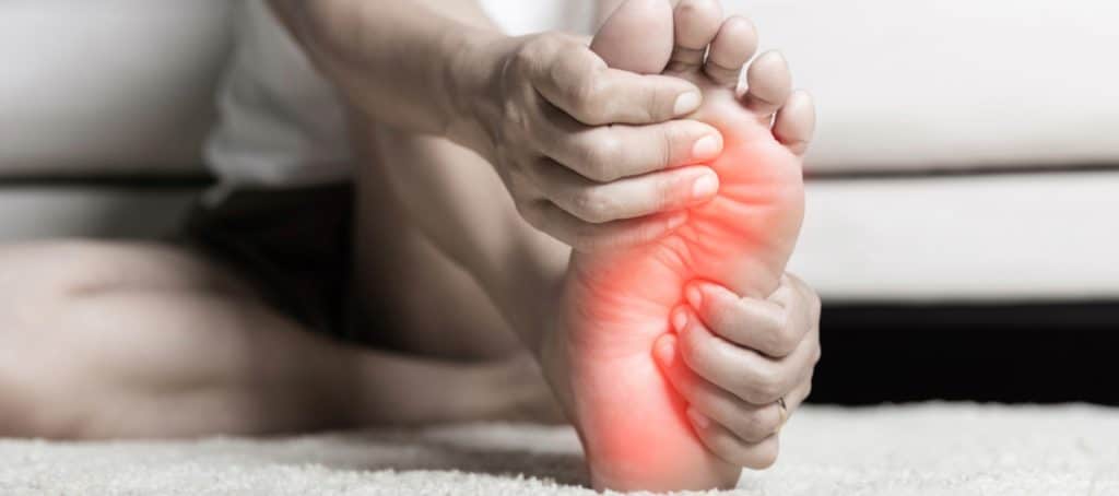 A woman grabs her foot due to diabetic neuropathy pain