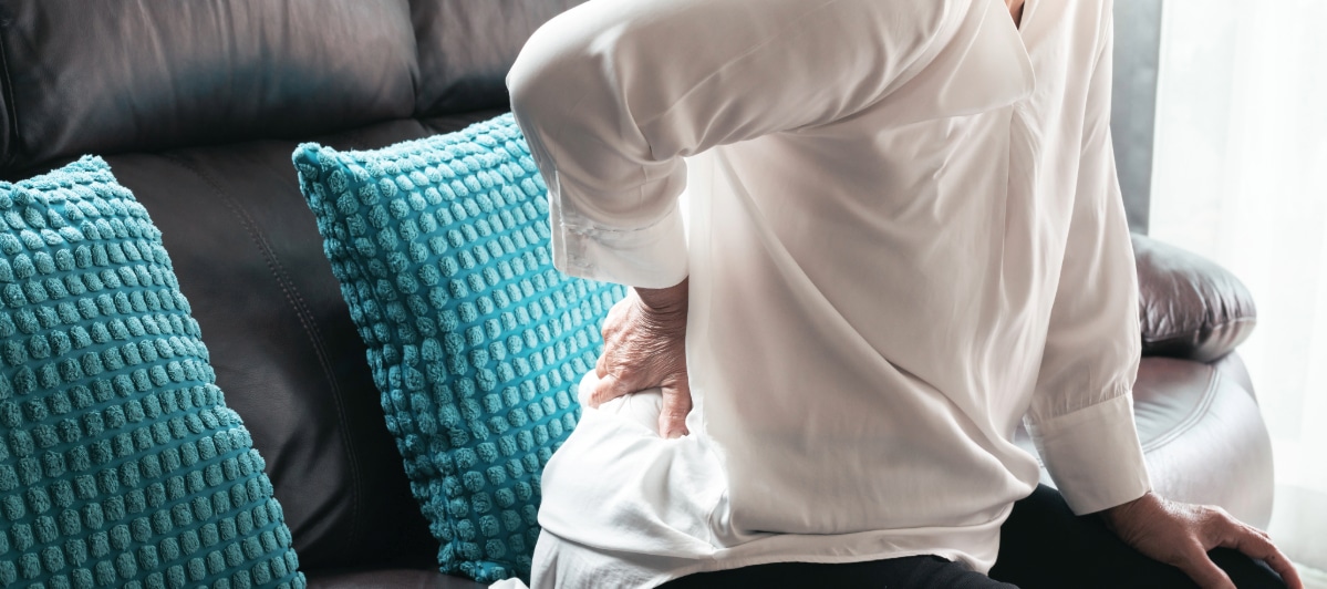 A woman holds her back in pain due to vertebral compression fractures
