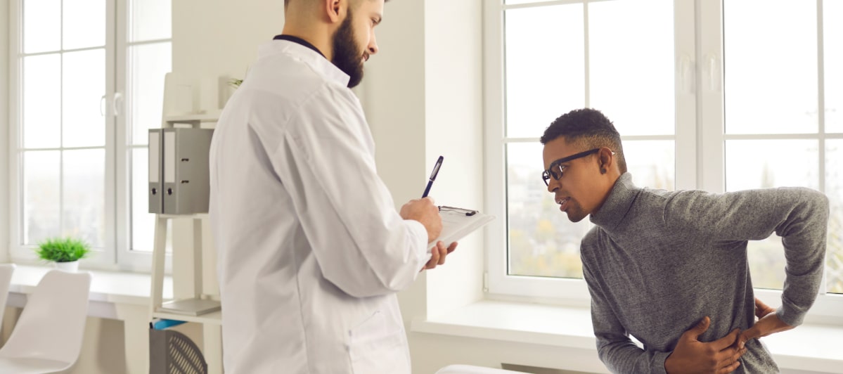 The Pros and Cons of Kyphoplasty-3-Patient A patient describes his vertebral compression fracture pain to a doctor in a lab coat