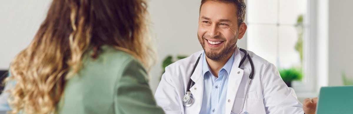 The Science Behind Glucose Measuring Strips-5 A doctor in a lab coat smiles as he talks with a patient about diabetes management with glucose measuring devices