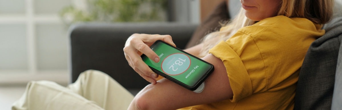 The Ultimate Guide to Blood Glucose Monitoring Kits-5 A woman uses her phone to check her glucose levels on an arm monitor